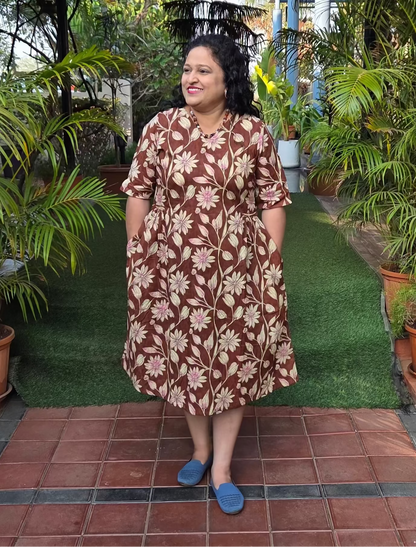 Woman in a patterned dress standing on a tiled path with greenery around